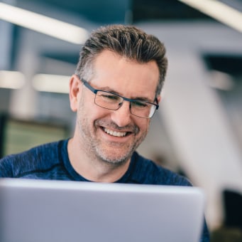 Man with glasses looking at his laptop